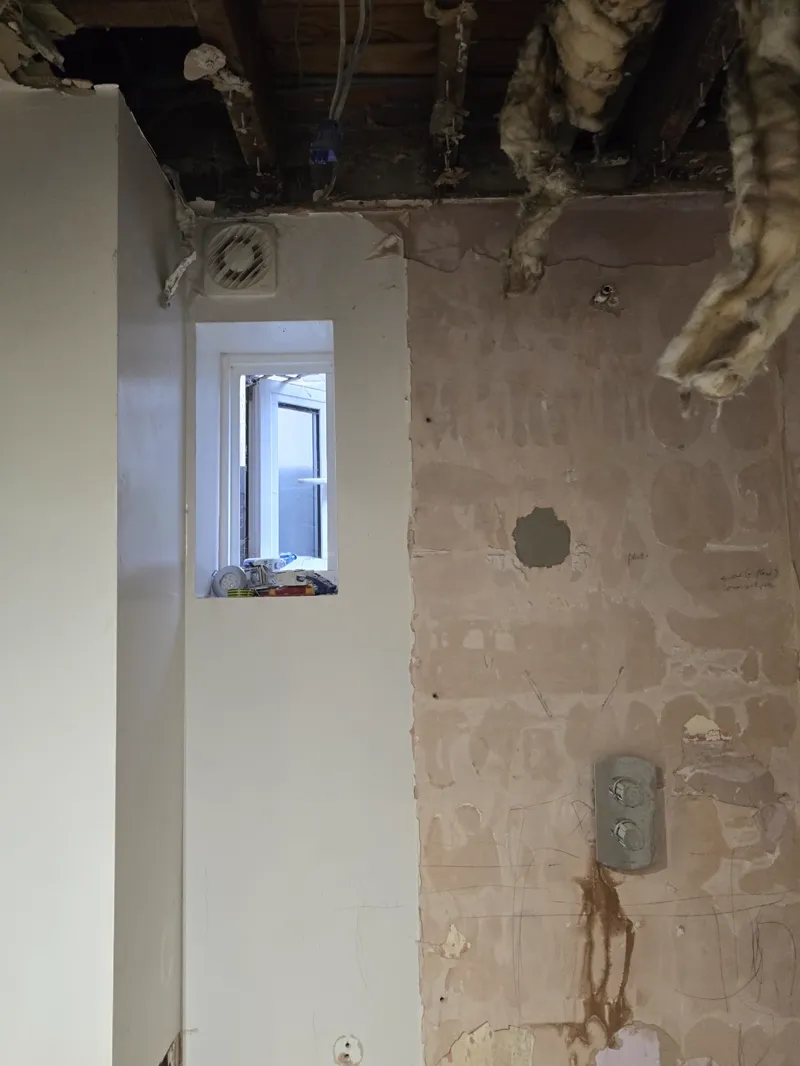 Roof-void strip-out showing ceiling joists, loft insulation and a first-fix electrical box.