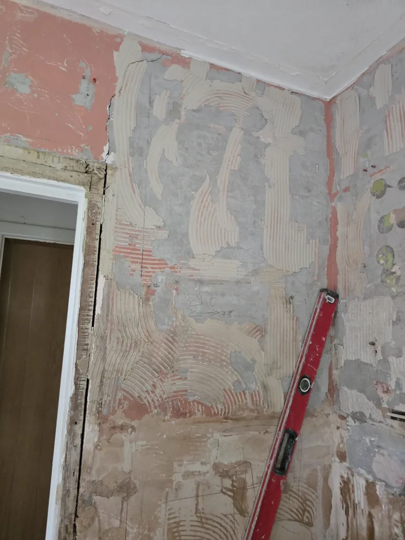 Freshly plaster-skimmed bathroom wall with bonding and finish coats visible.